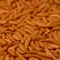 柿の種のあられ、オレンジ色の米菓、塩辛い味わいの写真