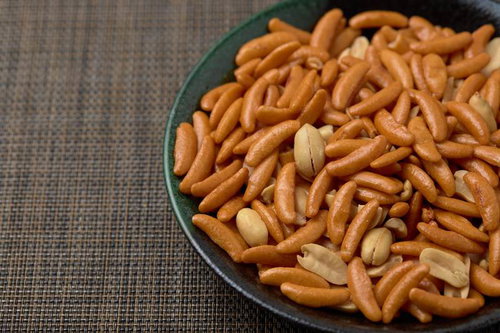 黒い皿に盛られたおつまみとして出された柿の種