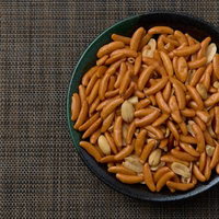 黒い器に盛った柿の種とピーナッツのおつまみの写真