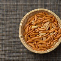 木製の笊に盛られた柿の種とピーナッツのおつまみの写真