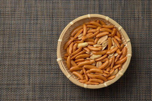 木製の笊に盛られた柿の種とピーナッツのおつまみ