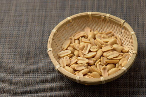 木製の笊に盛られたピーナッツと落花生の食品