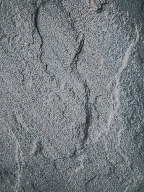 灰色の岩肌に亀裂や凹凸が走る岩の表面テクスチャー