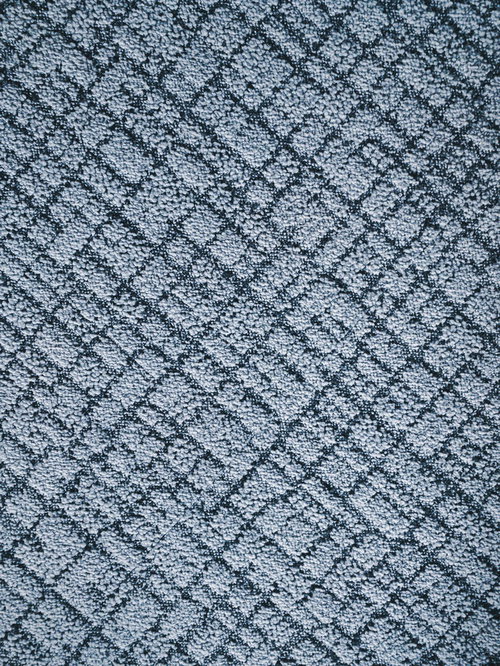 グレーの絨毯に織り込まれた幾何学模様のテクスチャー
