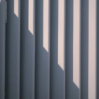 囲いのフェンスにかかる光と影の縦縞テクスチャーの写真