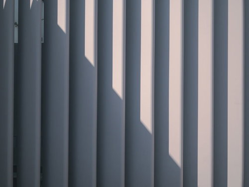 囲いのフェンスにかかる光と影の縦縞テクスチャー