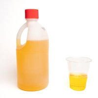 希釈した黄色い除草剤をコップに計量する農薬の準備作業の写真