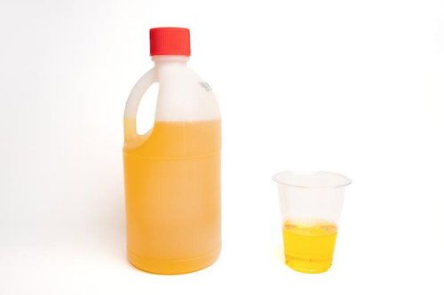 希釈した黄色い除草剤をコップに計量する農薬の準備作業