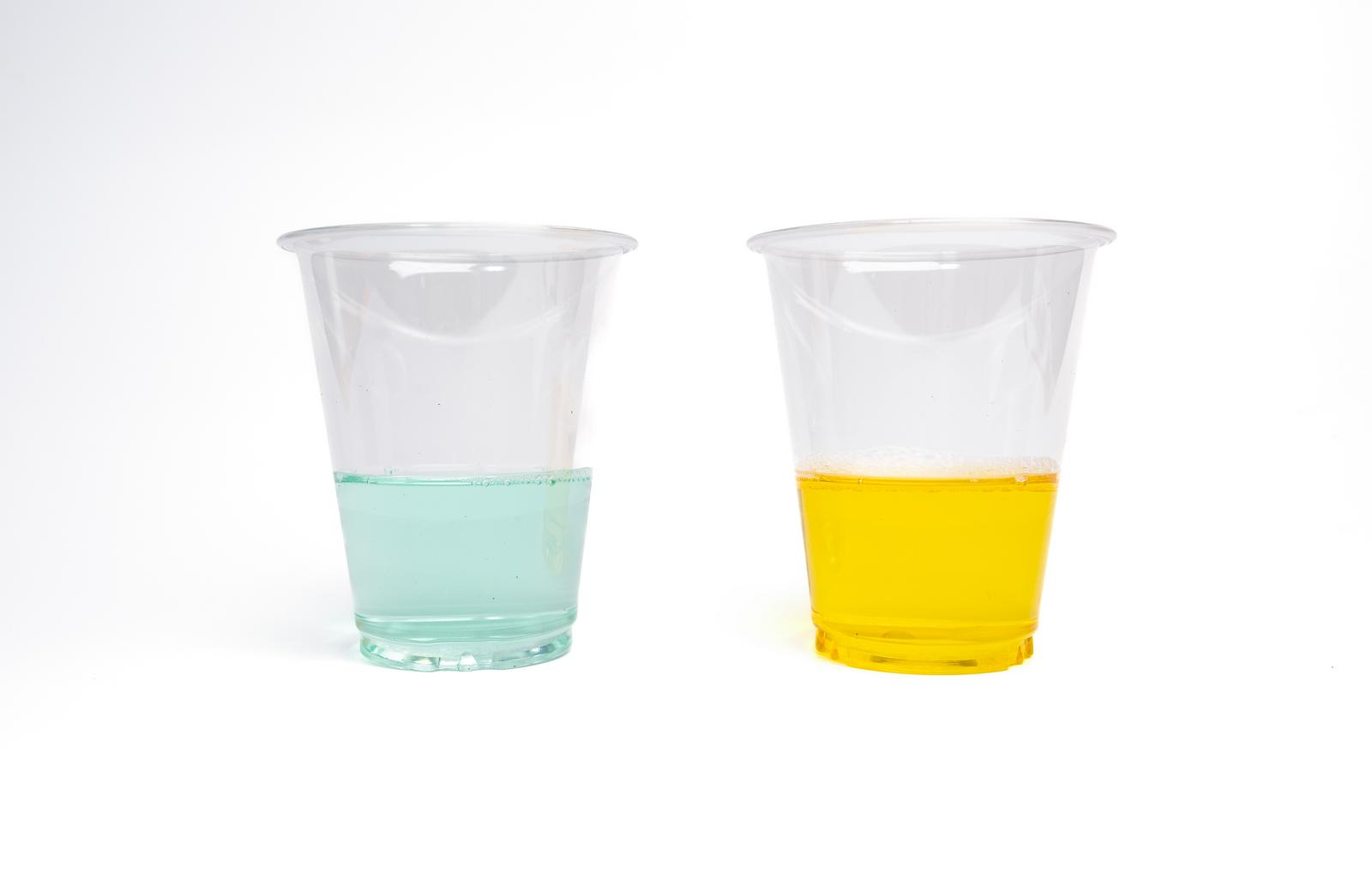透明カップに入った緑と黄色の液体。左が緑色、右が黄色の除草剤と実験用化学薬品