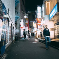 夜の道玄坂小路に並ぶ店舗と行き交う人々の街角風景の写真