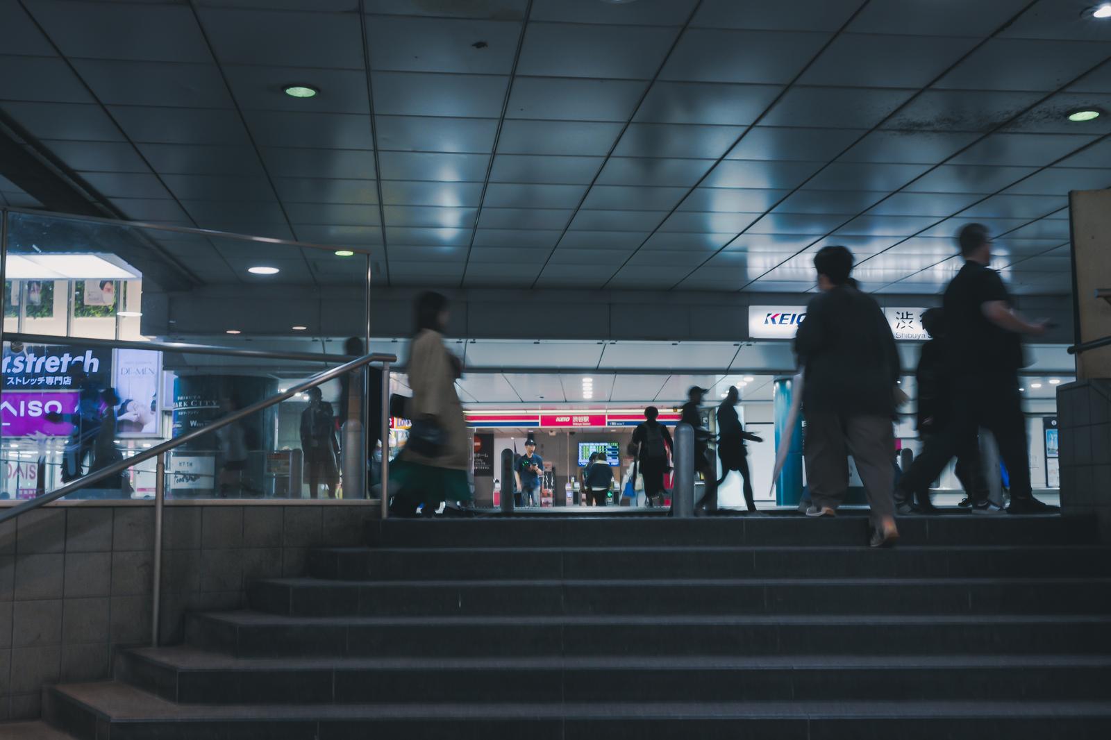渋谷駅の地下通路で階段を利用する人々と京王線の看板