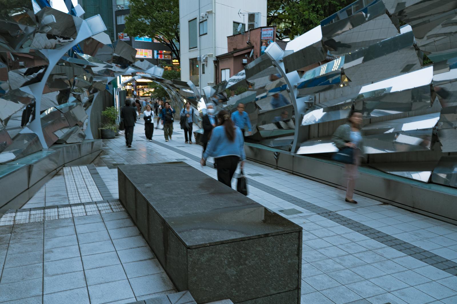 渋谷マークシティ入口の現代アート彫刻と通勤する人々の歩行風景