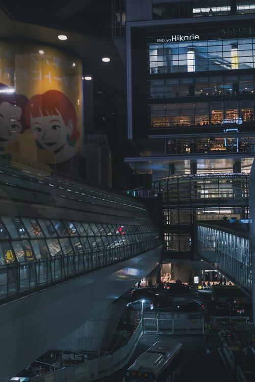 夜の渋谷ヒカリエビルとガラス張り通路、ネオンに照らされた街並み