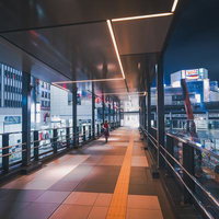 夜景に輝く東京渋谷の歩道橋通路、ネオン看板が映り込むガラス張り連絡通路の写真