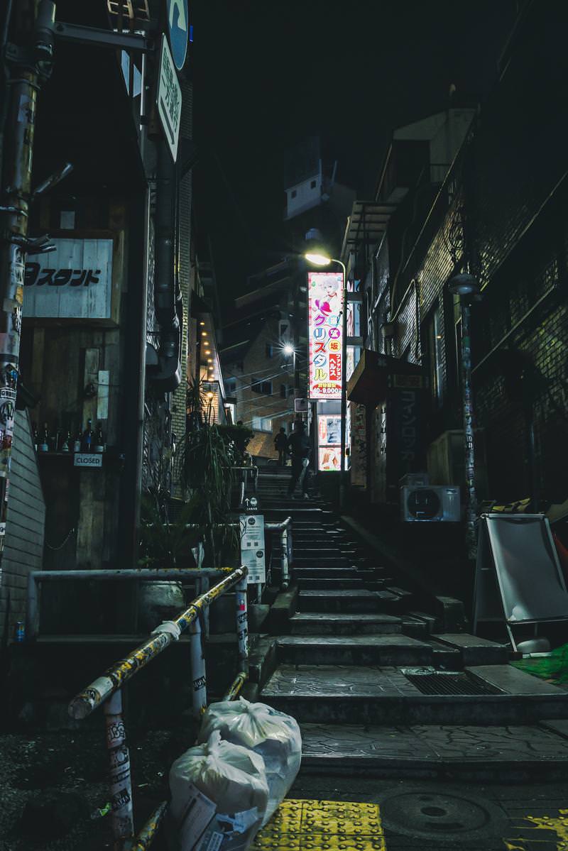 夜間の道玄坂小路階段路地、両脇の建物と飲食店の灯りが照らす様子