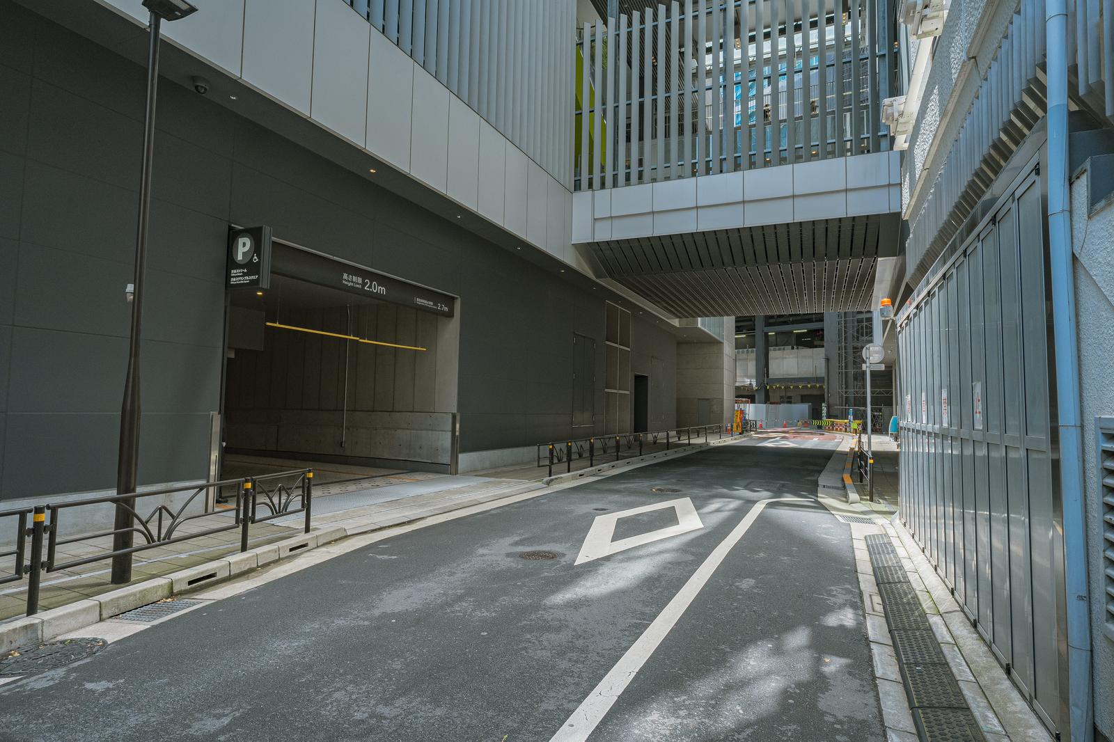 工事中の駐車場入口に立つ高さ制限2.0m看板と周囲の建設現場の様子