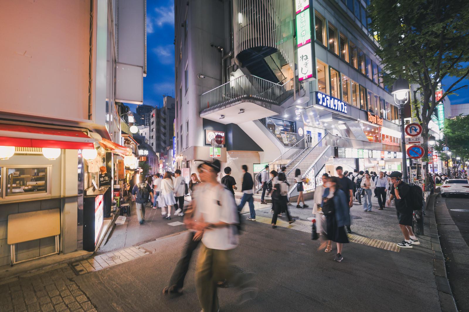 夜間の渋谷・道玄坂小路入口。照明が灯る店舗と多くの人が行き来する様子