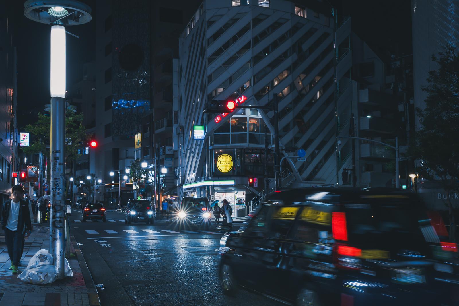 雨の夜間の渋谷松濤文化村ストリート、走行するタクシーと赤信号