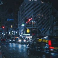 雨上がりの夜間の松濤文化村ストリート、赤い信号と走行タクシーの写真