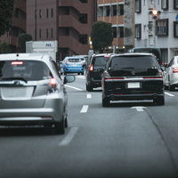 車間距離を取って公道を走行する自動車の車列の写真