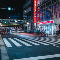 新大久保駅前の夜間の横断歩道を渡る歩行者と繁華街の夜景の写真