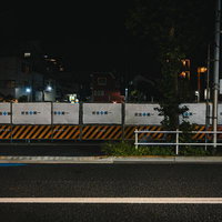 夜間の工事現場に立つ安全第一の黄黒フェンスの写真