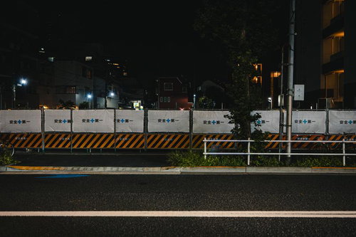 夜間の工事現場に立つ安全第一の黄黒フェンス