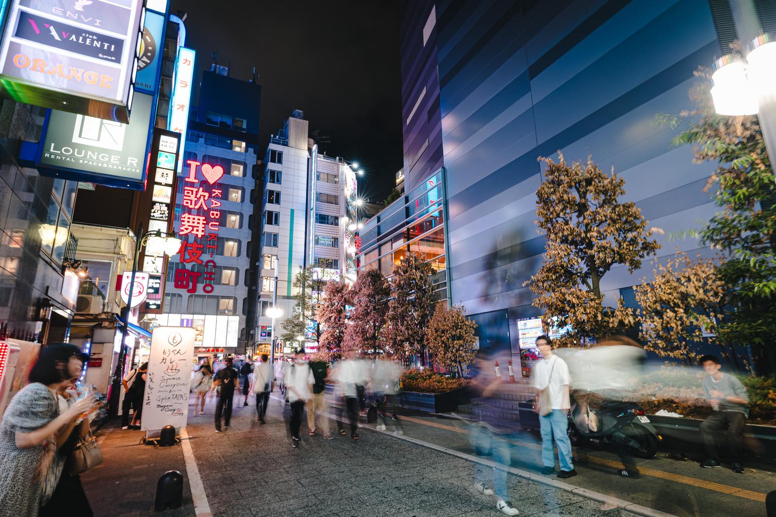 ネオン看板が輝く新宿歌舞伎町トー横通りで人々が行き来する夜間の繁華街風景