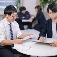 オープンスペースで資料を確認するビジネスマンと女性社員の写真