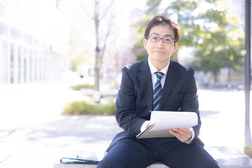 街中で資料を持つ営業部長の爽やかなポートレート