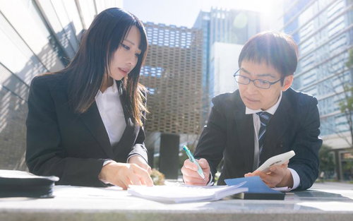 ビジネス街で営業資料を確認する上司と部下の女性