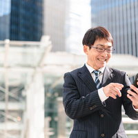 嬉しい報告が入って笑みがこぼれるビジネスマン上司の写真