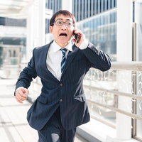 慌てて本社に戻る部長、スマホで電話しながら走るの写真