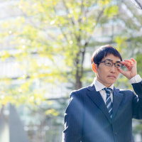 メガネをクイと持ち上げるスーツ姿の営業男性の写真