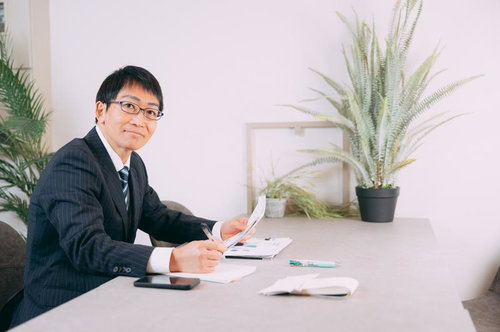 デスクで資料を確認する笑顔の面接官の採用試験