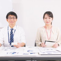 会議室で資料を見ながら打ち合わせする男性部長と女性社員の写真