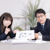 プレゼン資料を見せて力説する男性と女性社員の写真