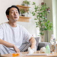 家でティッシュを手に鼻炎に悩む男性のポートレートの写真