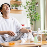 花粉症で鼻をかむ男性がティッシュを持つ様子の写真