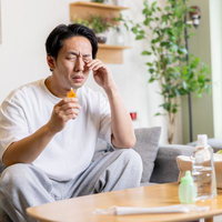 花粉症で目のかゆみが止まらない男性が目薬をさすの写真