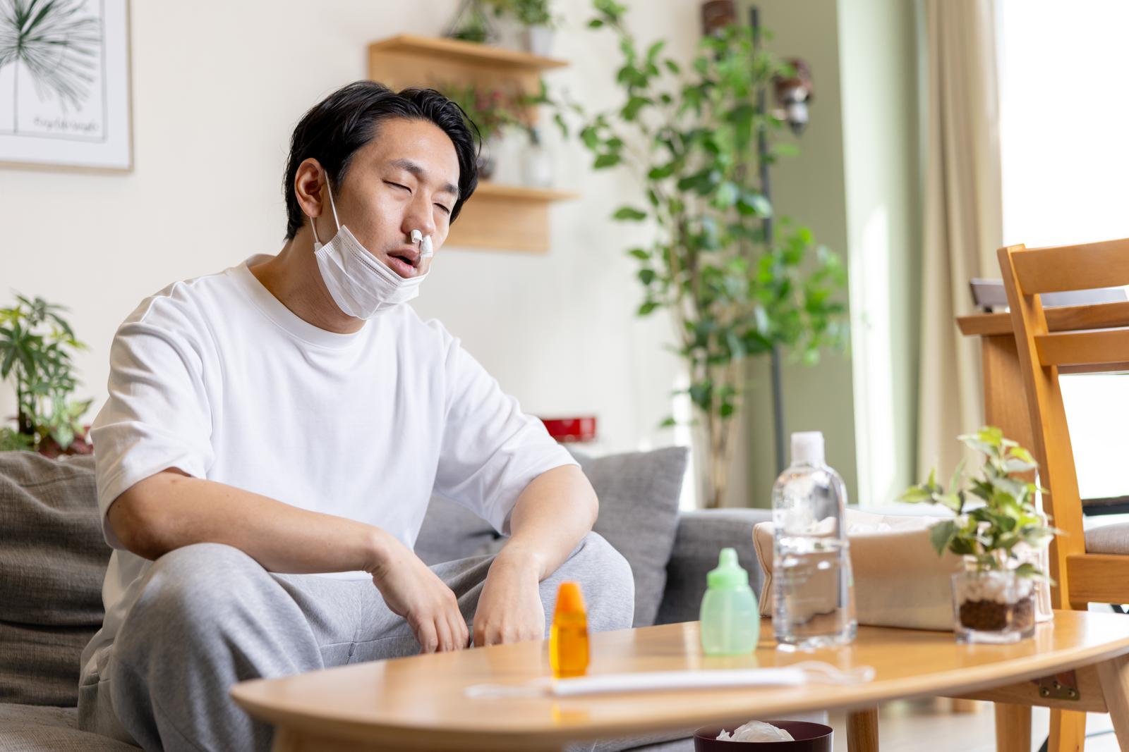 鼻にティッシュを詰めてうつむく男性［モデル：大川竜弥］