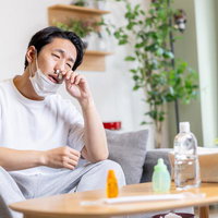マスクを外して鼻炎の症状に苦しむ男性の花粉症対策の写真