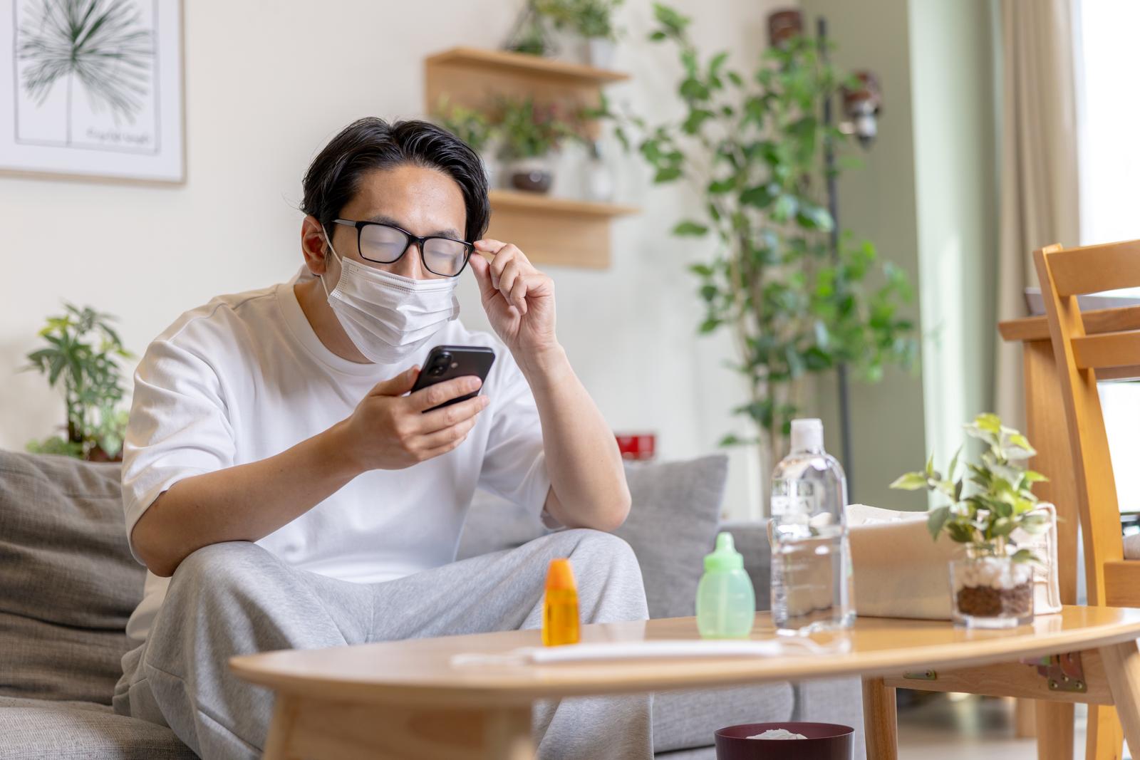 マスクをしてメガネが曇り、スマホが見えなくなって困っている男性［モデル：大川竜弥］