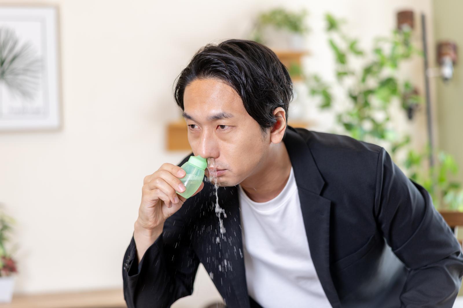 緑色の鼻洗浄ボトルで鼻うがいする男性［モデル：大川竜弥］
