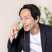 鼻洗浄液を使って鼻をスッキリさせ笑顔になる男性の写真