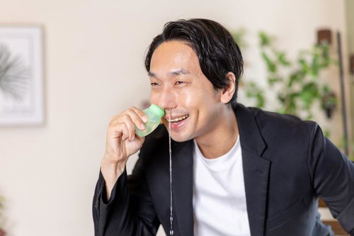 鼻洗浄液を使って鼻をスッキリさせ笑顔になる男性