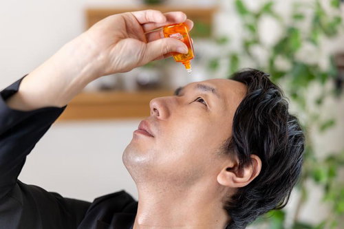 目薬を点眼する男性、花粉症やドライアイ対策のアイケア