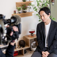 ビデオカメラの取材を受けるアラフォーの男性の写真