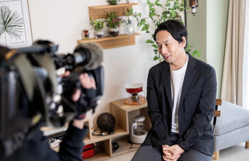 ビデオカメラの取材を受けるアラフォーの男性