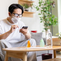 眼鏡が曇った状態でもスマホを見続ける鼻炎の男性の写真